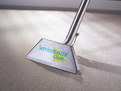 Two cleaning people are cleaning the inside of a classroom by wiping down desks and using a microfiber mop to wipe dust and debris off floors