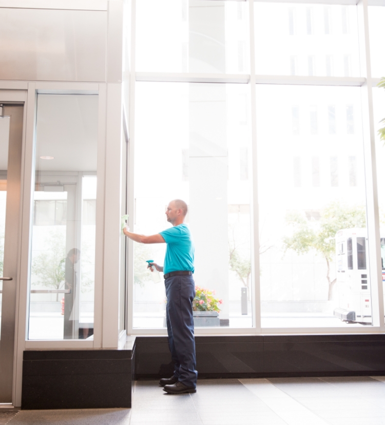 A ServiceMaster technician sanitizing a window in an office building lobby during commercial window cleaning services in St. Cloud, Minnesota