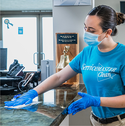 Cleaning person is wiping down a counter height countertop in an office waiting room