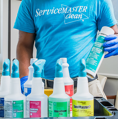 Cleaning person picking up a Sanimaster proprietary cleaning solution from cart full of supplies