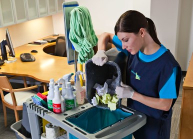 woman emptying trash into a janitorial cart