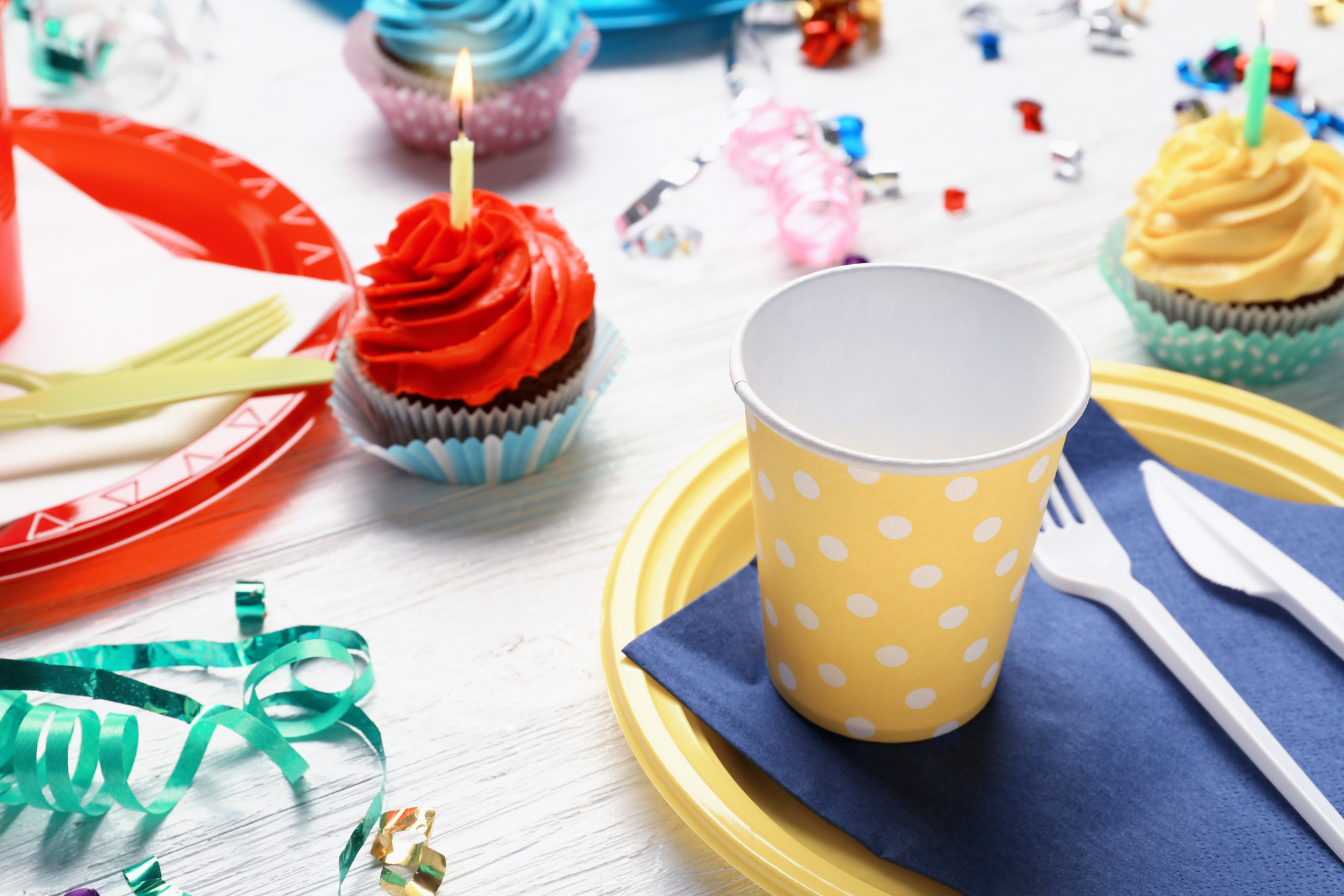 Table set with colorful plates and cupcakes