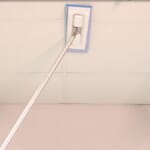 Person using tool to clean a ceiling