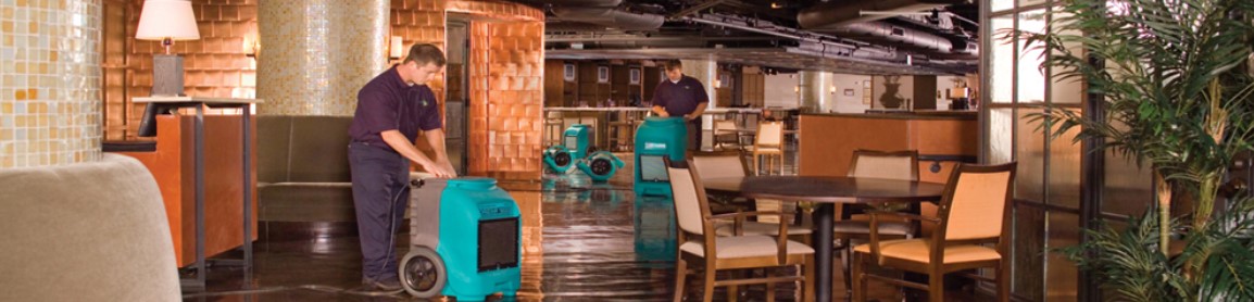 two techs using machines to clean a flooded area
